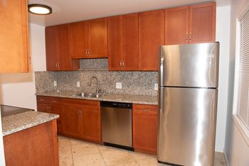 A kitchen with a stainless steel refrigerator and wooden cabinets.